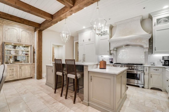 kitchen with high end range, hanging light fixtures, a notable chandelier, a kitchen island, and custom exhaust hood