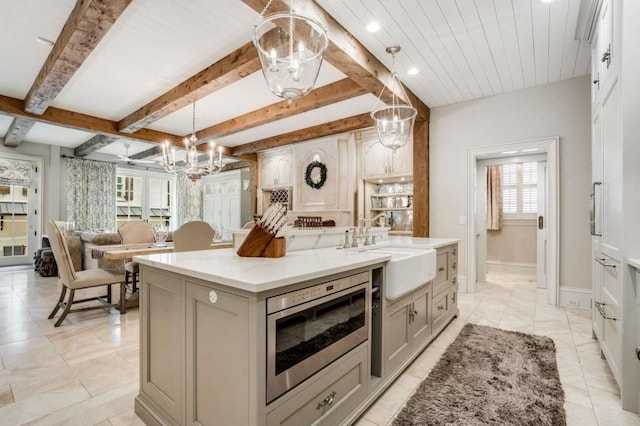 kitchen featuring sink, decorative light fixtures, a notable chandelier, beamed ceiling, and a large island