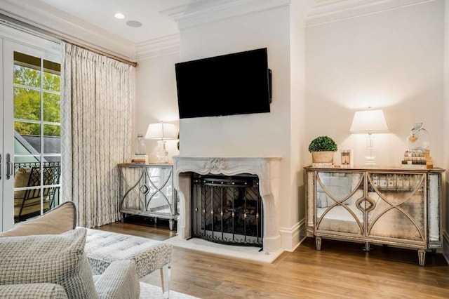 living area featuring crown molding, wood-type flooring, and a high end fireplace