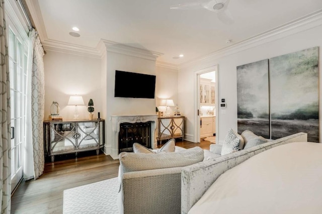 living room with wood-type flooring, ornamental molding, ceiling fan, and a fireplace