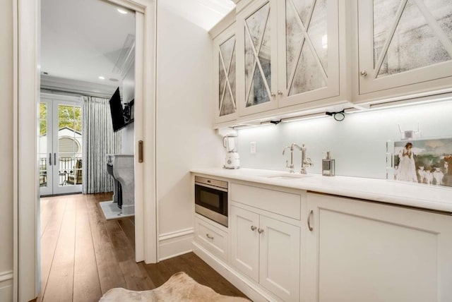 bar with white cabinetry, sink, and dark hardwood / wood-style flooring