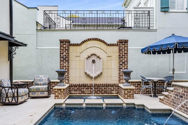 view of swimming pool with pool water feature and a patio area