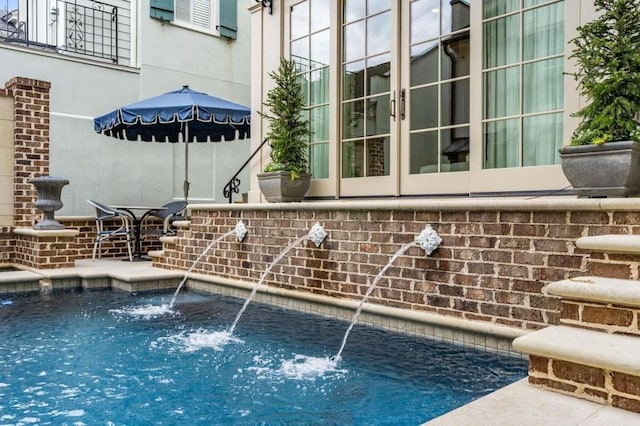 view of pool with pool water feature and french doors