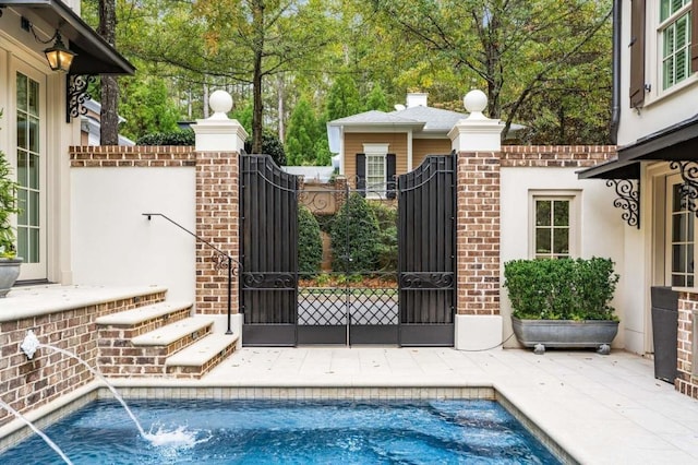 view of gate with a fenced in pool and pool water feature