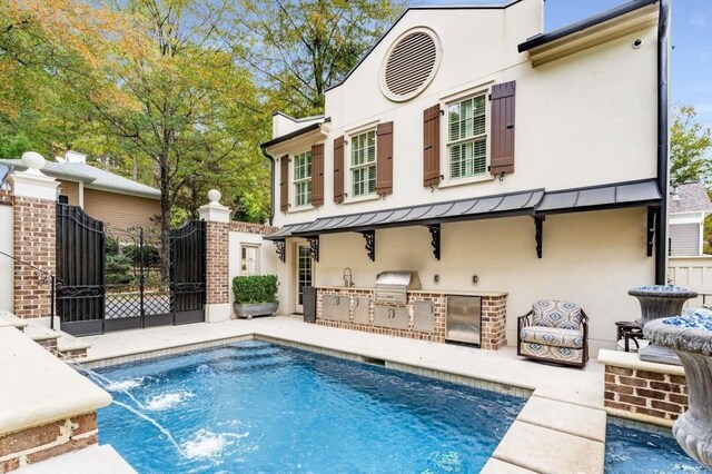 back of house featuring a patio, pool water feature, and exterior kitchen