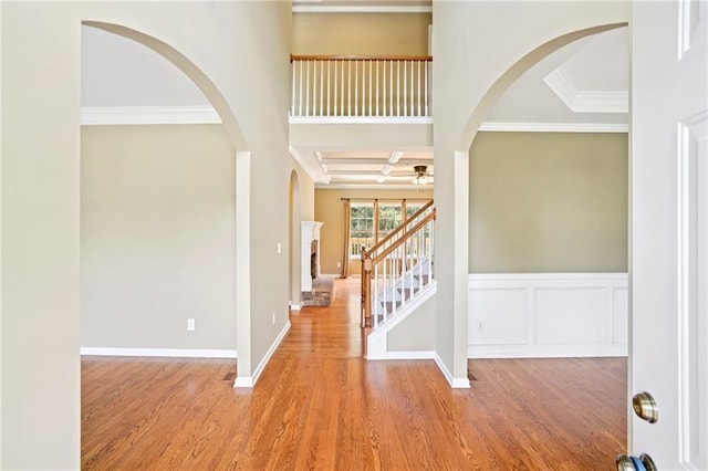 2359 Saint Kennedy Ln, Buford, GA 30518 - foyer entrance with arched walkways, wood finished floors, a ceiling fan, ornamental molding, and a fireplace with raised hearth