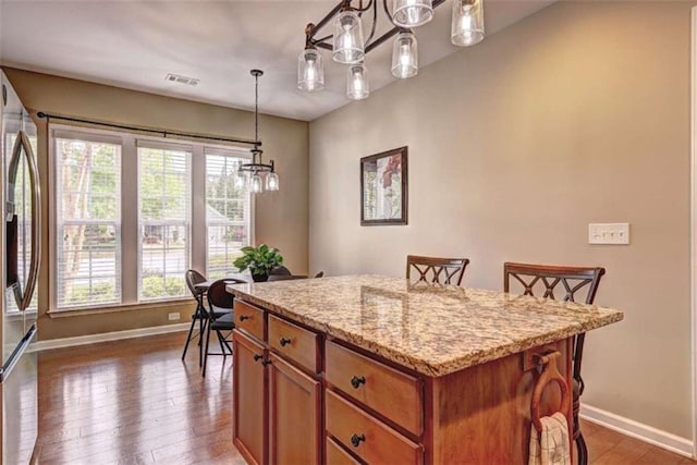 802 Dusky Sap Ct, Griffin, GA 30223 - kitchen featuring brown cabinets, dark wood-type flooring, light stone countertops, stainless steel refrigerator with ice dispenser, and a center island