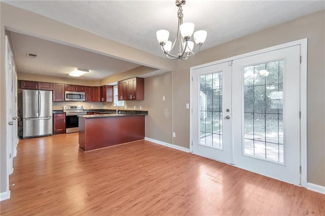912 Third St, Stone Mountain, GA 30083 - kitchen with appliances with stainless steel finishes, dark countertops, a chandelier, a peninsula, and light wood-type flooring