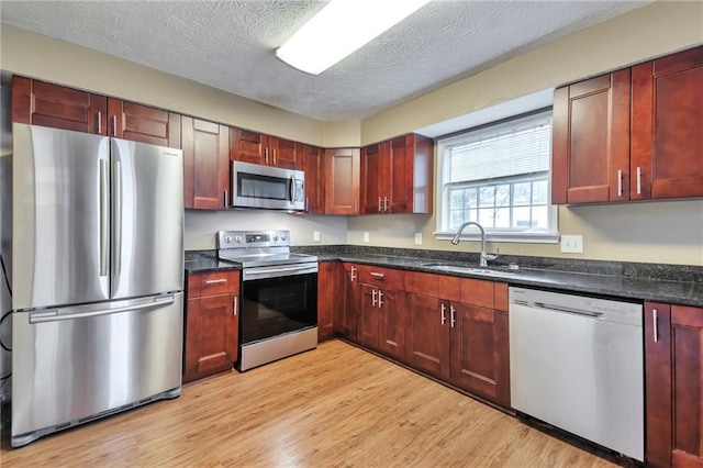 912 Third St, Stone Mountain, GA 30083 - kitchen featuring stainless steel appliances, dark brown cabinets, a sink, light wood-type flooring, and a textured ceiling