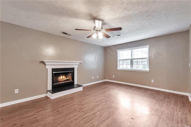 912 Third St, Stone Mountain, GA 30083 - unfurnished living room featuring wood finished floors, ceiling fan, baseboards, a warm lit fireplace, and a textured ceiling