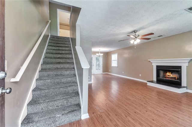 912 Third St, Stone Mountain, GA 30083 - staircase featuring wood finished floors, ceiling fan, a glass covered fireplace, baseboards, and a chandelier