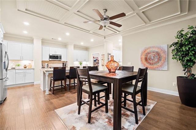 dining area with a ceiling fan, wood finished floors, baseboards, and coffered ceiling