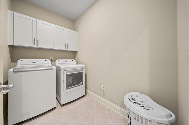 laundry area with cabinet space, washing machine and dryer, baseboards, and light tile patterned flooring