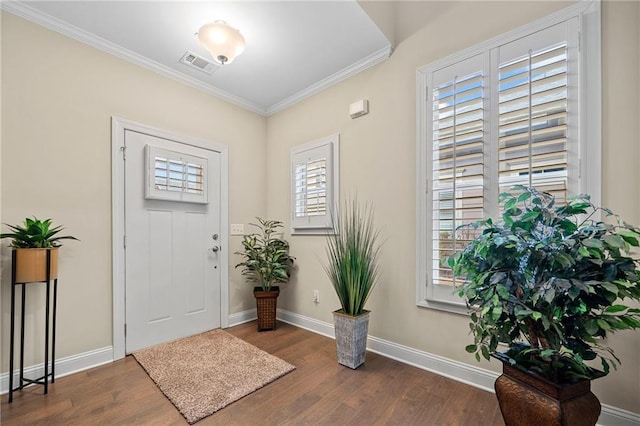 entryway with visible vents, wood finished floors, baseboards, and ornamental molding