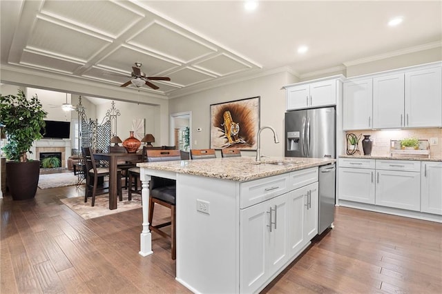 kitchen featuring stainless steel fridge with ice dispenser, hardwood / wood-style floors, a fireplace, white cabinets, and a sink