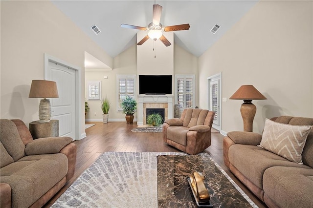 living room with a tiled fireplace, visible vents, high vaulted ceiling, and hardwood / wood-style floors