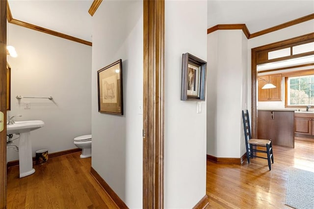 hallway with sink, ornamental molding, and light hardwood / wood-style flooring