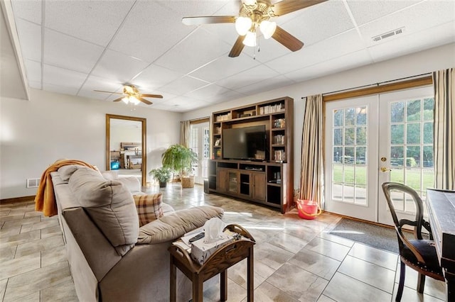 living room with ceiling fan, a paneled ceiling, and french doors