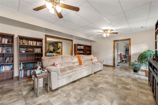 living room with a drop ceiling and ceiling fan