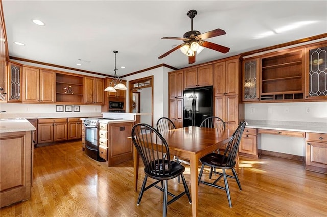 kitchen featuring built in desk, black appliances, light wood-type flooring, a kitchen island, and pendant lighting