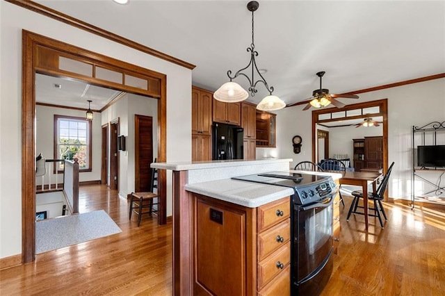 kitchen featuring light hardwood / wood-style floors, black appliances, and crown molding