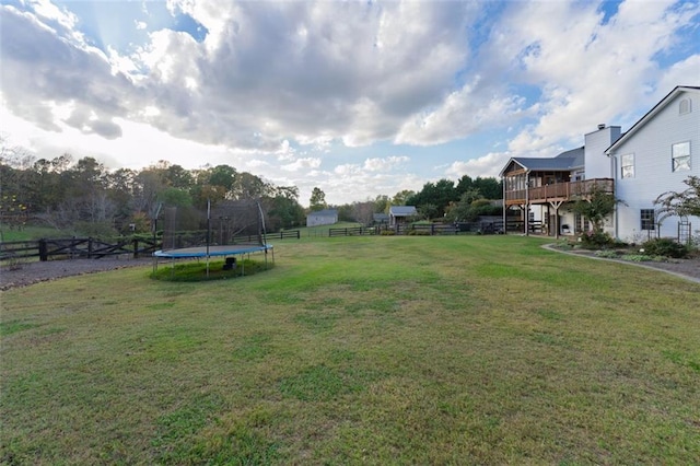 view of yard with a trampoline and a deck