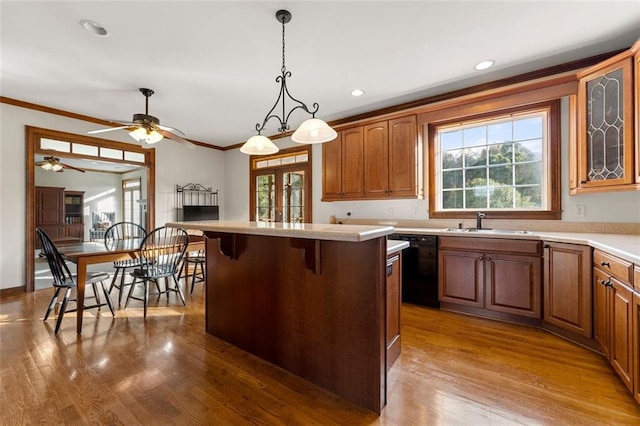 kitchen with a center island, dishwasher, crown molding, a breakfast bar, and light hardwood / wood-style flooring