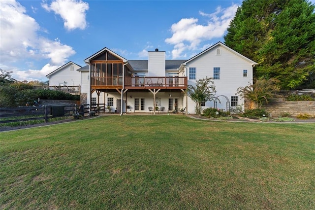 back of house with a wooden deck, a sunroom, and a yard