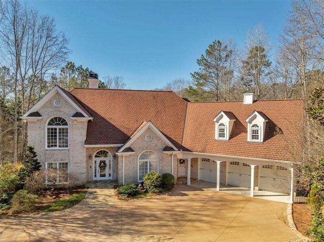 view of front of property with a garage, french doors, driveway, and a chimney