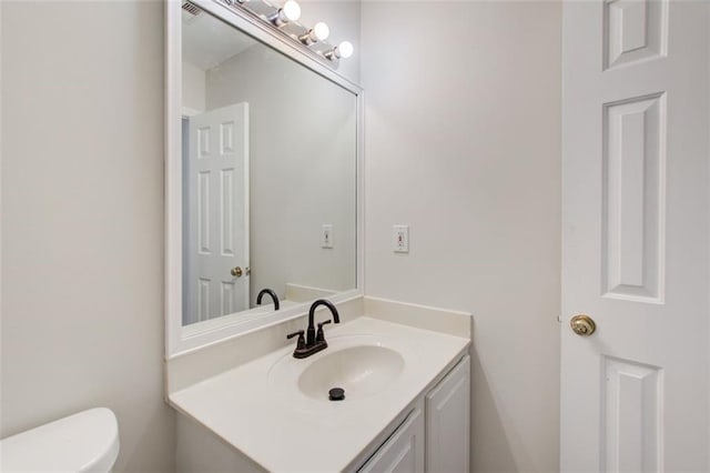 bathroom with toilet and vanity with extensive cabinet space