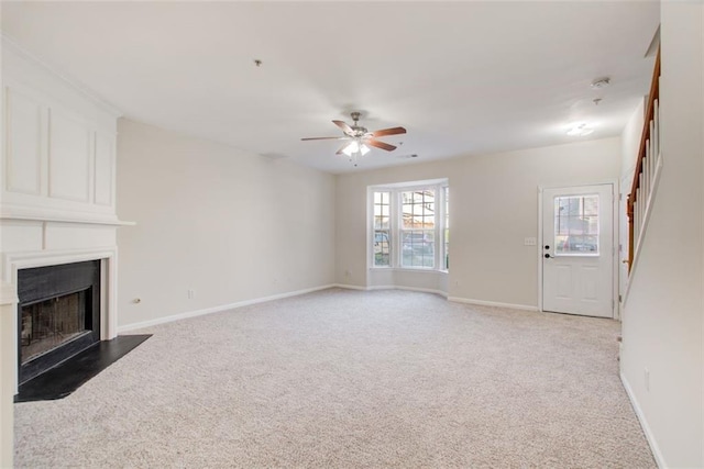 unfurnished living room with light colored carpet and ceiling fan