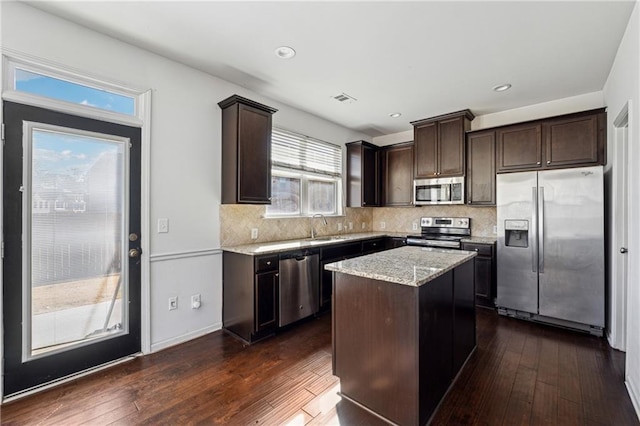 kitchen with a kitchen island, dark wood-type flooring, stainless steel appliances, sink, and backsplash