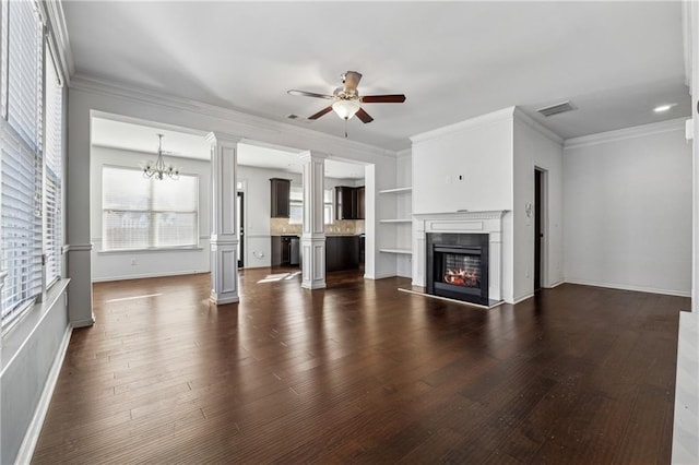 unfurnished living room with ceiling fan with notable chandelier, crown molding, built in features, and dark hardwood / wood-style floors