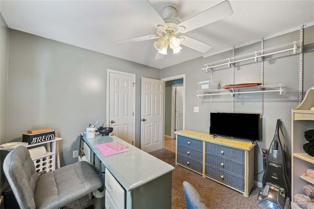 carpeted office space featuring ceiling fan