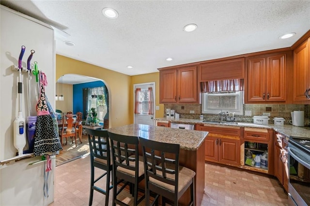 kitchen featuring sink, light stone counters, tasteful backsplash, a center island, and stainless steel appliances