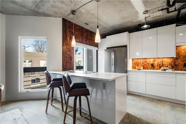 kitchen featuring white cabinetry, stainless steel fridge, a breakfast bar, and plenty of natural light