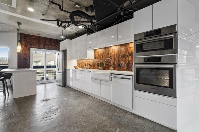 kitchen with decorative light fixtures, white cabinetry, sink, a breakfast bar area, and stainless steel appliances