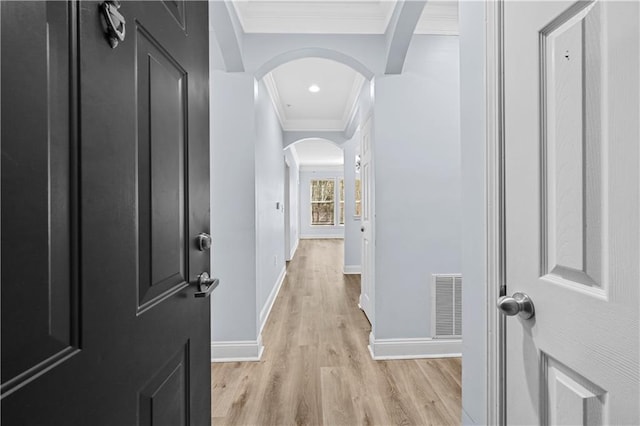 hallway featuring ornamental molding and light hardwood / wood-style floors