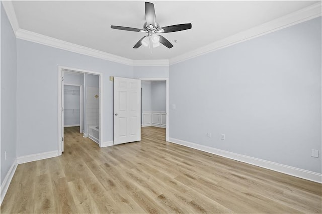 unfurnished bedroom featuring light wood-type flooring, a closet, ornamental molding, a spacious closet, and ceiling fan