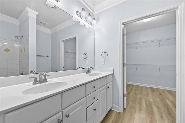 bathroom featuring crown molding, wood-type flooring, tiled shower, and vanity