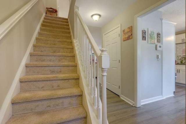 stairway with wood finished floors and baseboards