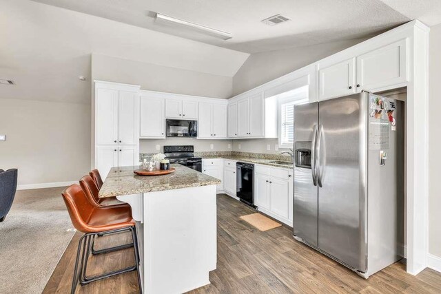 kitchen with black appliances, vaulted ceiling, baseboards, white cabinetry, and a center island