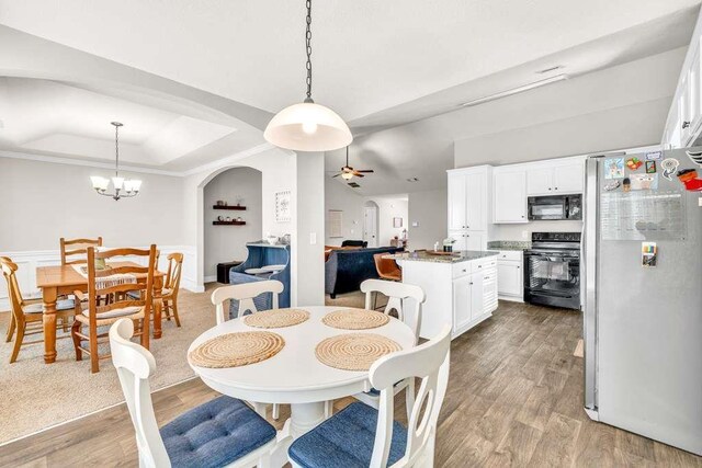 dining space featuring a ceiling fan, light wood-style floors, a raised ceiling, a chandelier, and crown molding