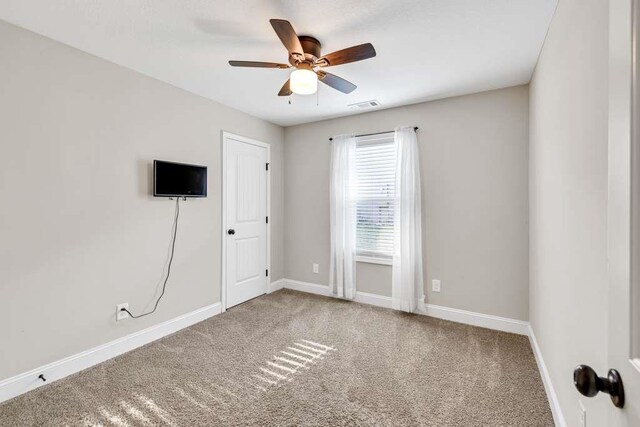 carpeted spare room featuring baseboards and ceiling fan