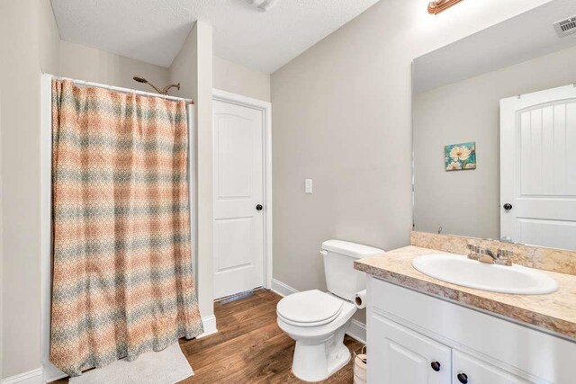 bathroom with toilet, wood finished floors, vanity, a shower with shower curtain, and baseboards