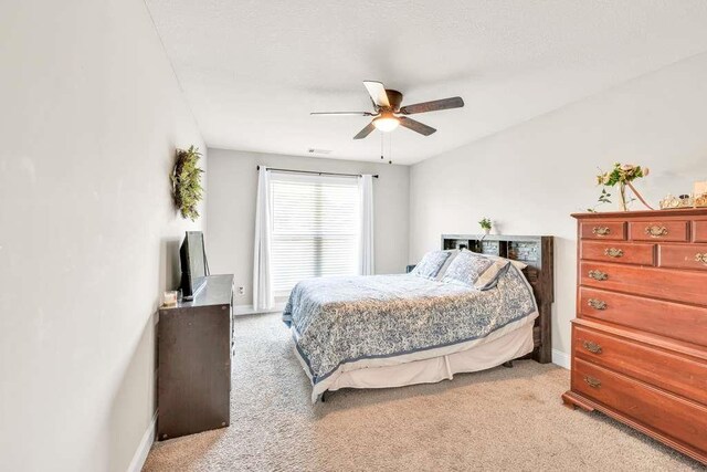 bedroom with light colored carpet, baseboards, and a ceiling fan