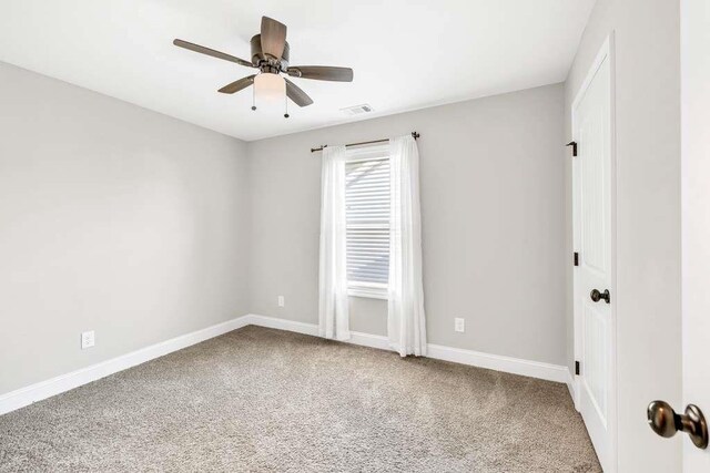carpeted spare room featuring baseboards and a ceiling fan