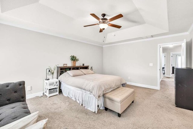 bedroom featuring a raised ceiling, light colored carpet, ornamental molding, baseboards, and a ceiling fan