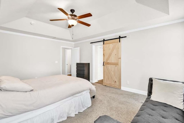 bedroom with a raised ceiling, a barn door, carpet flooring, baseboards, and crown molding