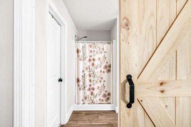 bathroom featuring wood finished floors, baseboards, and a shower with shower curtain